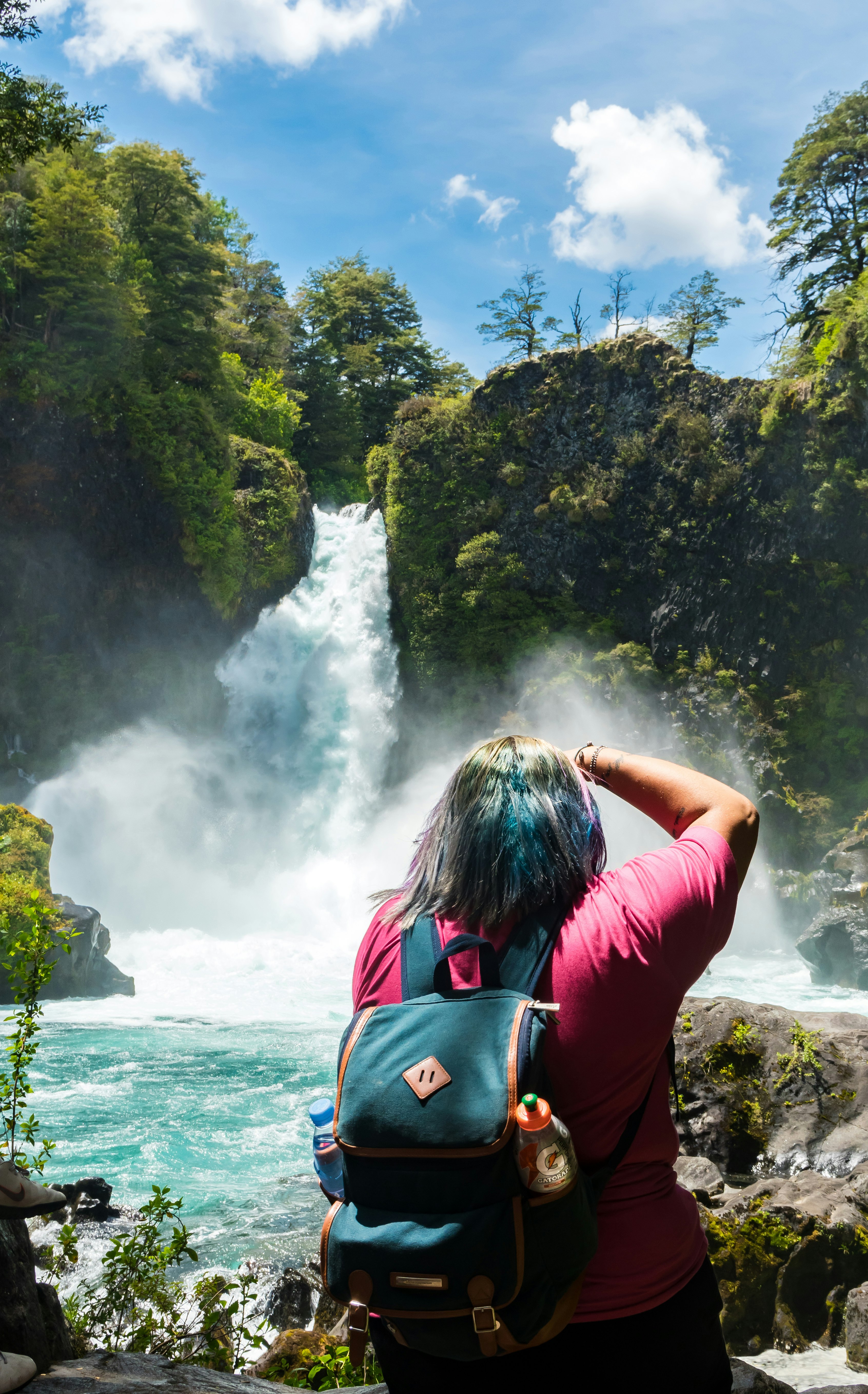 person in pink shirt looking at running waterfalls at daytime